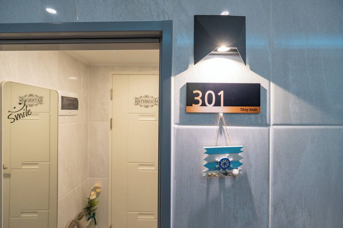 A bathroom with a sign reading '301 Stay jade' and a decorative piece below it.