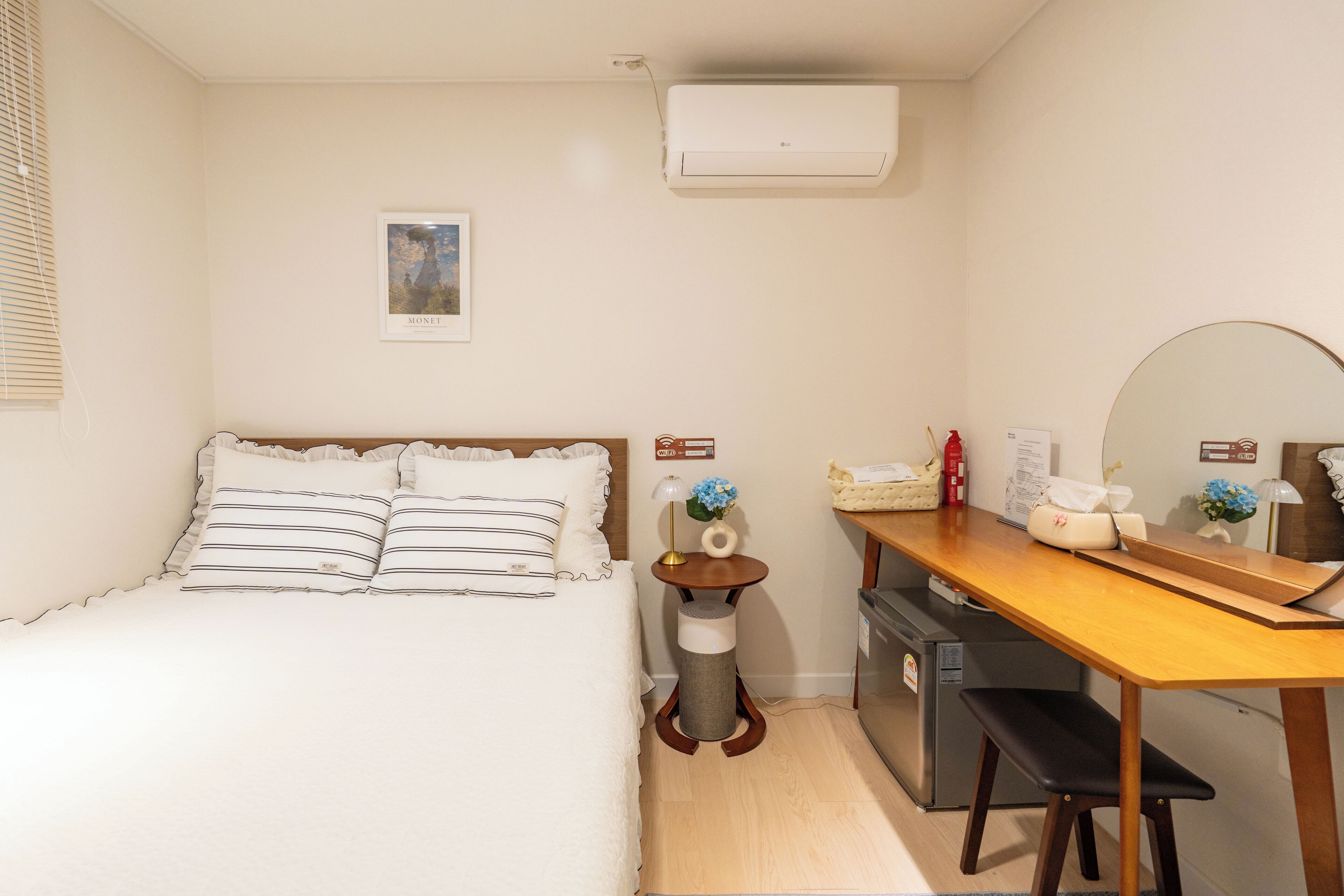 A bedroom with a bed, bedside table, lamp, and a small trash bin.