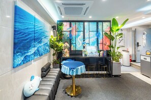 A modern hotel lobby with a blue ocean mural, a reception desk, a seating area, and a large plant. - STAY JADE (Seoul)