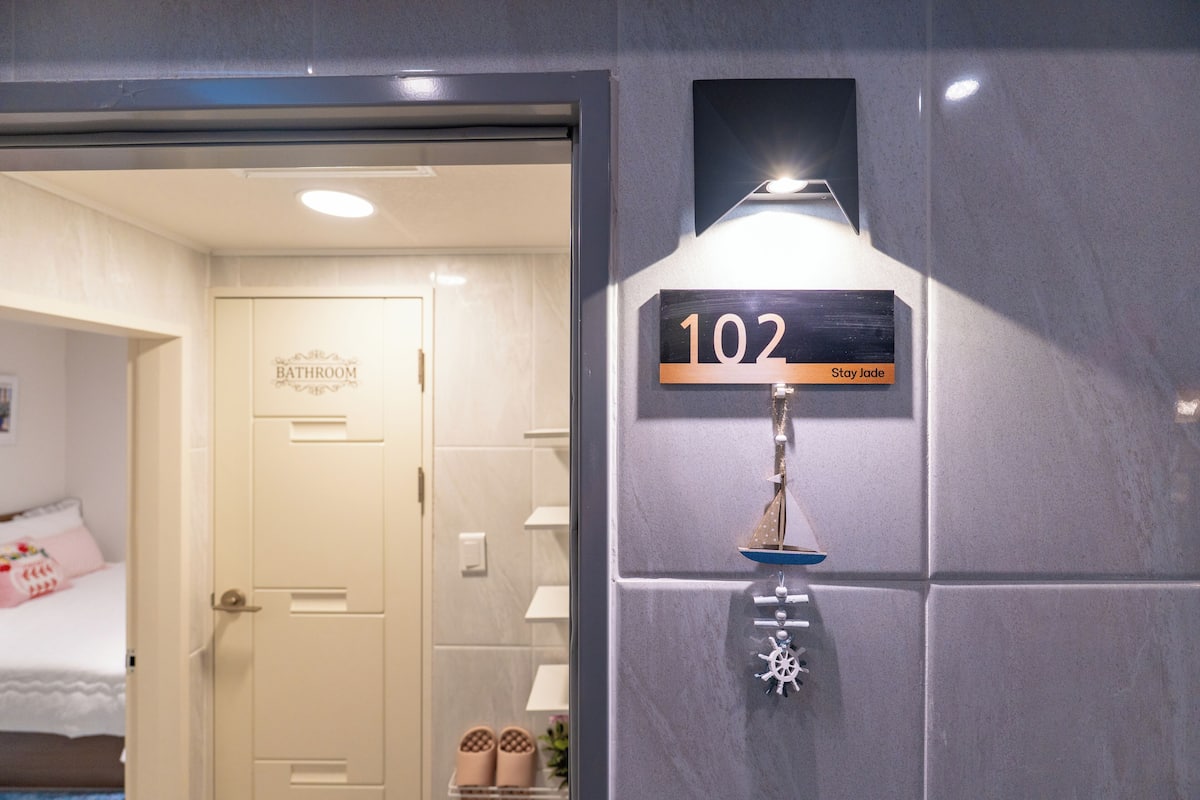 A bathroom with a sign indicating room number 102 and a decorative ship ornament.