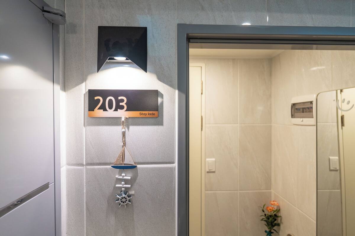 A bathroom with a vanity, a towel rack, a shower area, and a flower vase.