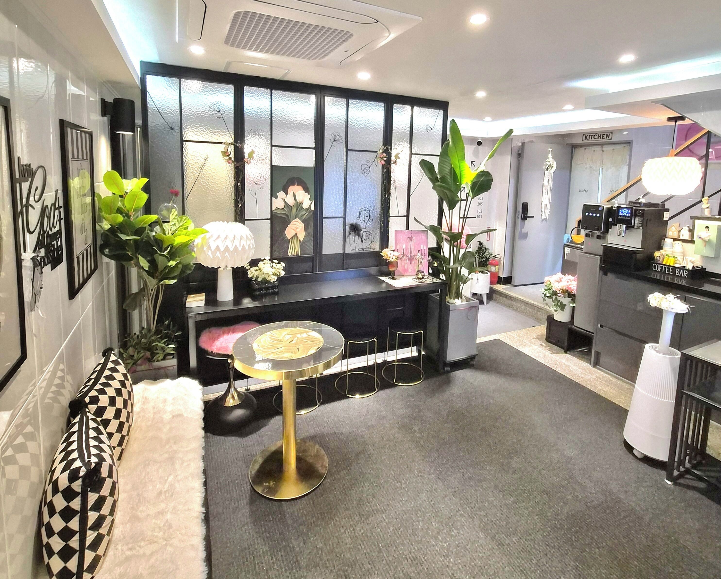 A modern hotel lobby with a reception desk, seating area, and a coffee bar.