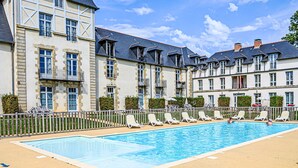 Un hotel con piscina, varios balcones y un estilo arquitectónico europeo tradicional.
