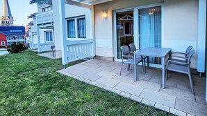 A modern building with a balcony, outdoor seating, and a view of a church spire. - Hotelpark Bodetal by Interhome (Thale)