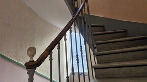 Spiraalimainen portaikko, jossa on puinen kaide ja metalliset koristepylväät.