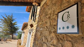 A stone building with a rustic wooden ceiling and a sign with a letter 'C' and stars. - CASA DE LA LUZ-FINCA LA SIERRA (Berzocana)