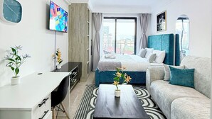 Ett modernt hotellrum med en säng, en soffa, ett skrivbord och en TV.