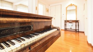 Un piano à queue dans une pièce bien éclairée, dotée d’un parquet en bois et d’un miroir au mur.