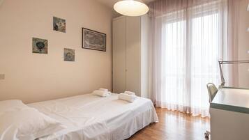 A bedroom with a single bed, a desk, and a chair. There are three framed pictures on the wall.