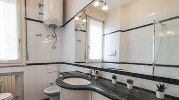 A modern bathroom with a white toilet, a sink with a black countertop, and a large mirror.