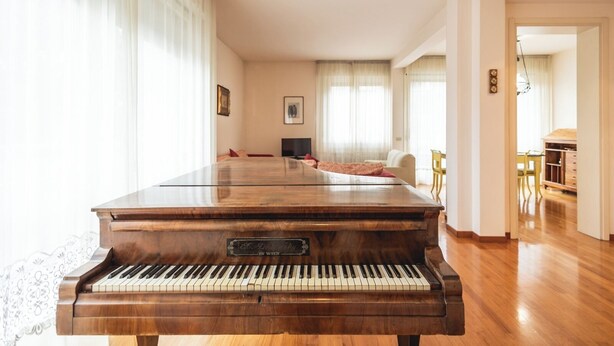 Un salon spacieux avec un magnifique piano à queue, un canapé confortable et un coin repas.