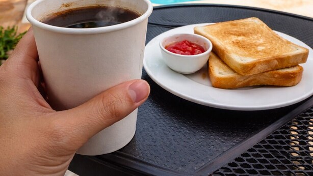 A hand holding a cup of coffee and toast with jam on a table by a pool. - Luna Studios 23  (Bacalar)