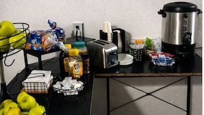 A breakfast setup with a toaster, a kettle, and various food items on a table. - Luna Studios 23  (Bacalar)