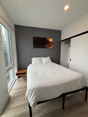 Ein Schlafzimmer mit einem Bett, einer Bank, einem Wandbild und einem Fenster.