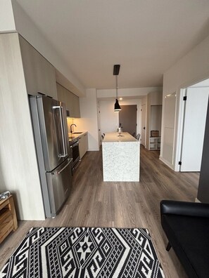 Une cuisine moderne dotée d’un îlot central, d’appareils électroménagers en acier inoxydable et d’un tapis à motifs.