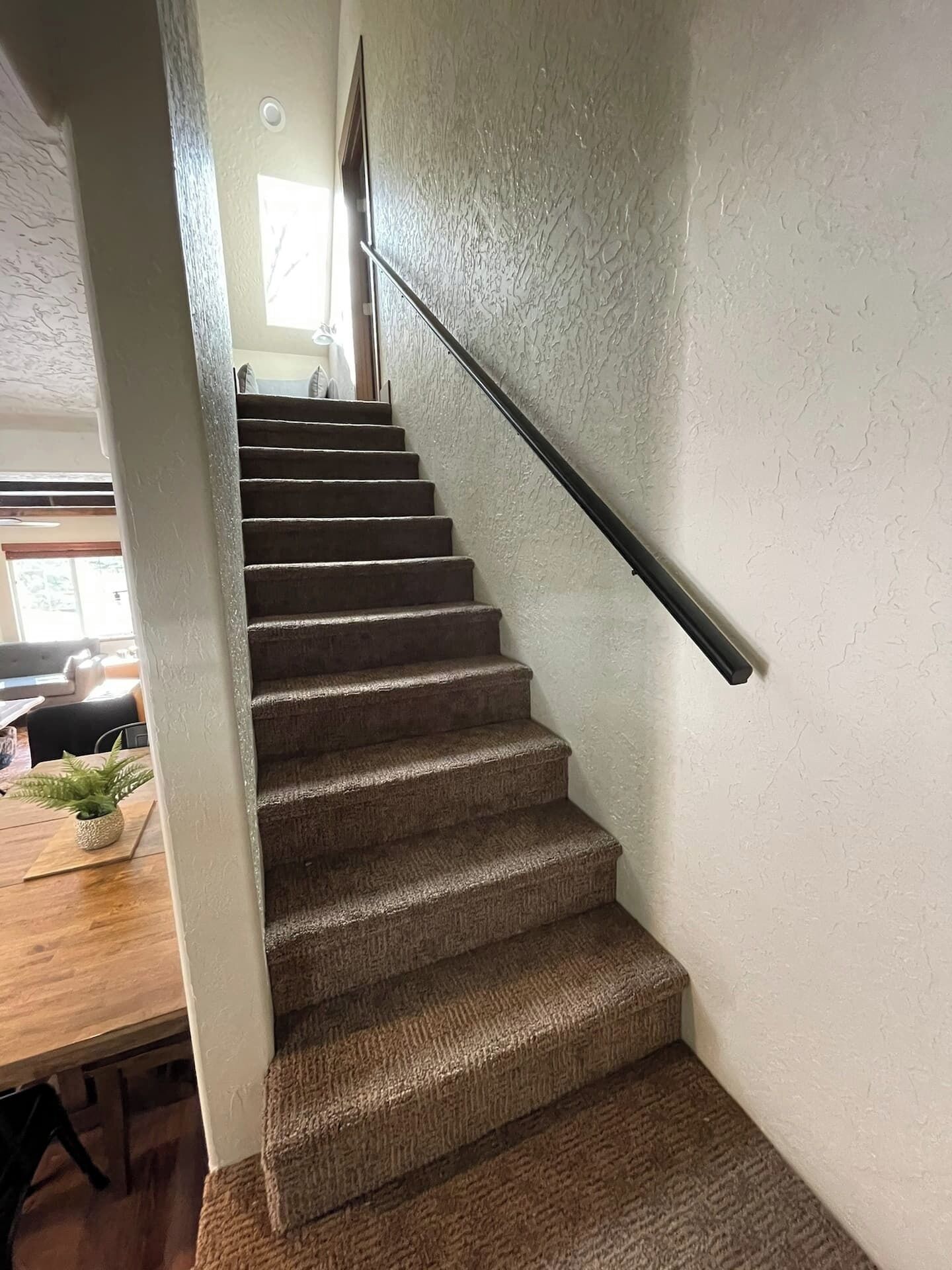 A carpeted staircase with a handrail, leading to an upper floor.