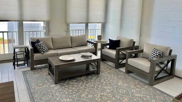 Un balcon spacieux avec un canapé, des fauteuils et une table basse.