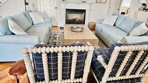 Un salon avec deux canapés bleu clair, une table basse en bois, une cheminée et un escalier.