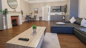 A living room with a fireplace, a dining area, a kitchen, and a seating area with a sofa and cushions. - Central Vista Retreat (Chester)