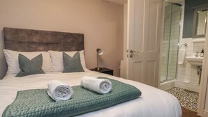 A neatly made bed with pillows, a green quilt, and rolled towels. - Central Vista Retreat (Chester)