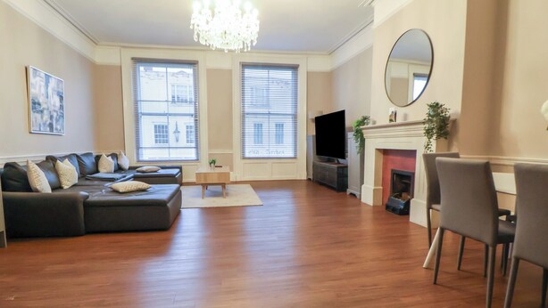 A spacious living room with a dark leather sectional sofa, a flat-screen TV, a fireplace, and a large mirror. - Central Vista Retreat (Chester)