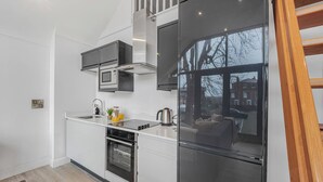Eine moderne Küche mit Einbauofen, Mikrowelle und Kühlschrank, einem großen Fenster und Blick ins Freie.