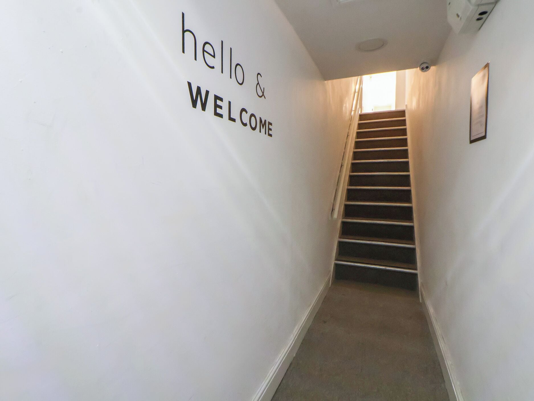 A staircase with a 'hello & welcome' sign on the wall.