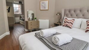 Et hotelværelse med seng, kommode, skrivebord og et vindue.