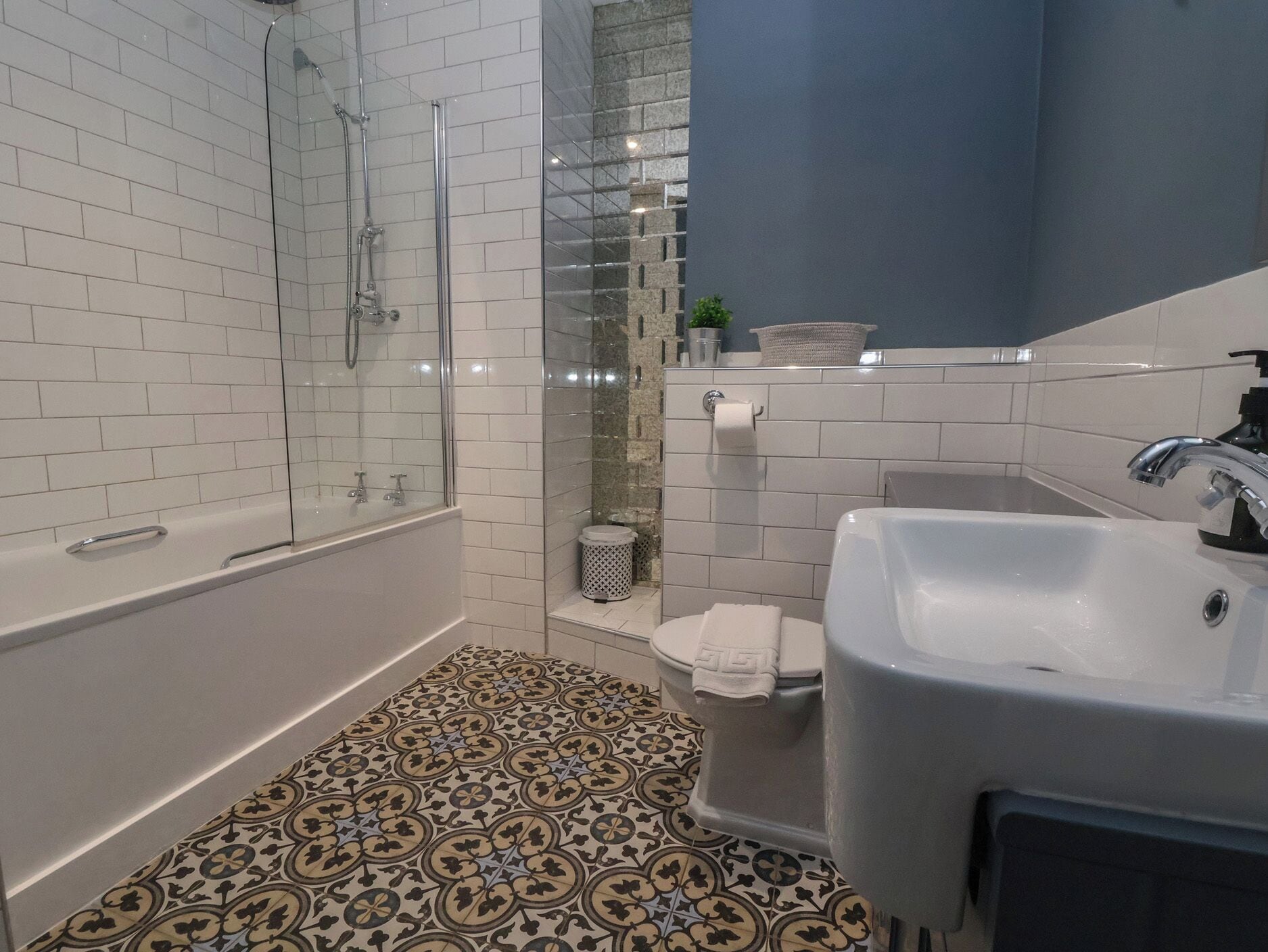 A modern bathroom with a glass-enclosed shower, a bathtub, a toilet, and a sink.