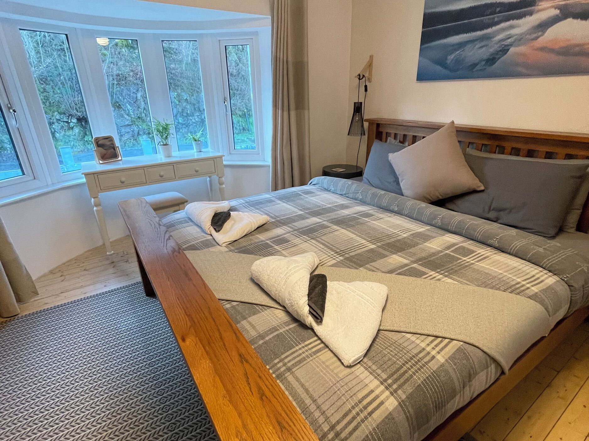 Ein Schlafzimmer mit einem Bett, einem Nachttisch, einer Lampe und einem Fenster mit Vorhängen.