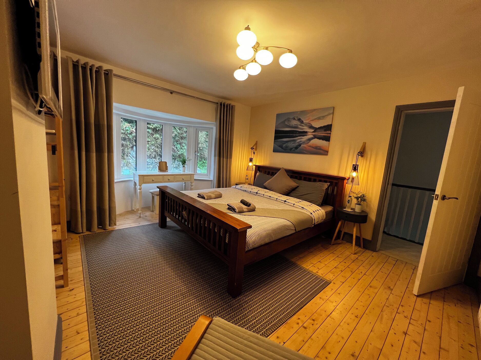 Ein Schlafzimmer mit einem hölzernen Bett, einem Schreibtisch und einem Fenster mit Vorhängen.
