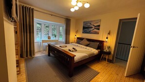 A bedroom with a wooden bed, a desk, and a window with curtains. - Dolwen (Caernarfon)