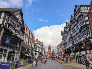 A historic street with traditional half-timbered buildings, a prominent clock tower, and a cobblestone street. - Southview Apartment (Chester)
