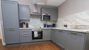 A modern kitchen with grey cabinets, a built-in oven, a microwave, and a marble backsplash. - Kingsley Loft (Chester)