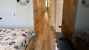 Un pasillo con una cama, un letrero de boya salvavidas y puertas de madera.