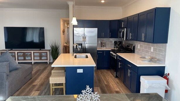 Una cocina moderna con armarios azul oscuro, una isla central y un comedor con mesa de madera.