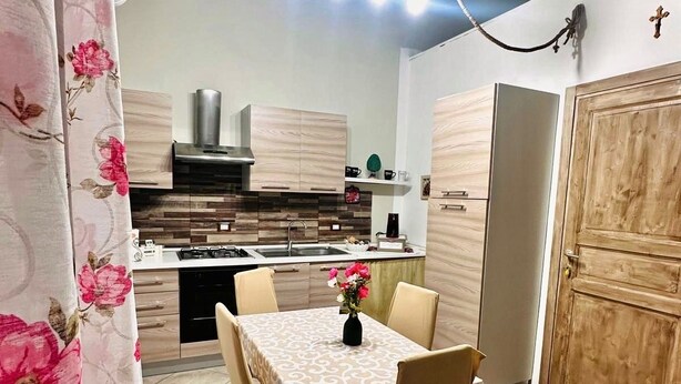 Un coin repas avec une table dressée pour quatre personnes, une cuisine en arrière-plan et une porte en bois.