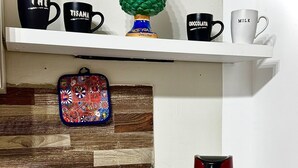 Un comptoir de cuisine avec une machine à café, un panier de biscuits et un panneau indiquant «café».
