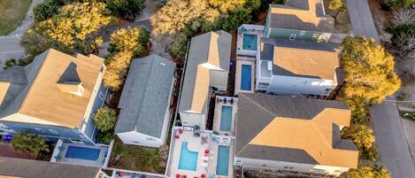 An aerial view of a residential area with multiple houses, a swimming pool, and a tennis court.