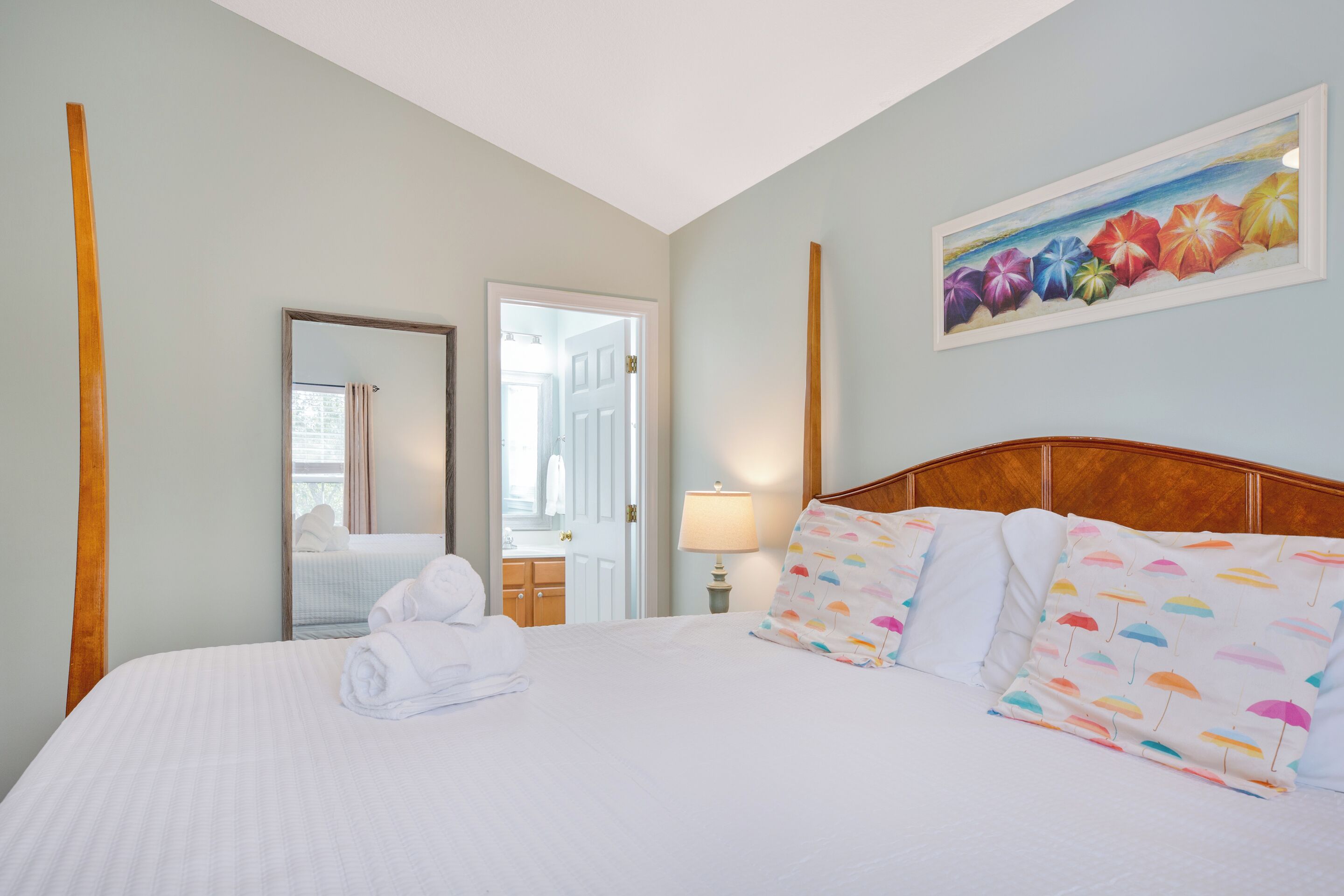 Ein Hotelzimmer mit Bett, Spiegel, Tür und einem Bild an der Wand.