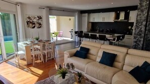 A modern living room with a sofa, coffee table, and dining area. - VILLA La Mazal, Bord de Mer, Balnéo, Piscine Clim (Sète)