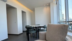 Un interior moderno con una zona de estar circular, una mesa de comedor con sillas y amplias ventanas con vistas a la ciudad.
