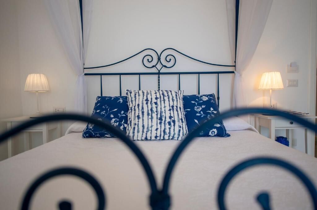 A neatly made bed with a headboard, two bedside lamps, and a patterned pillow.