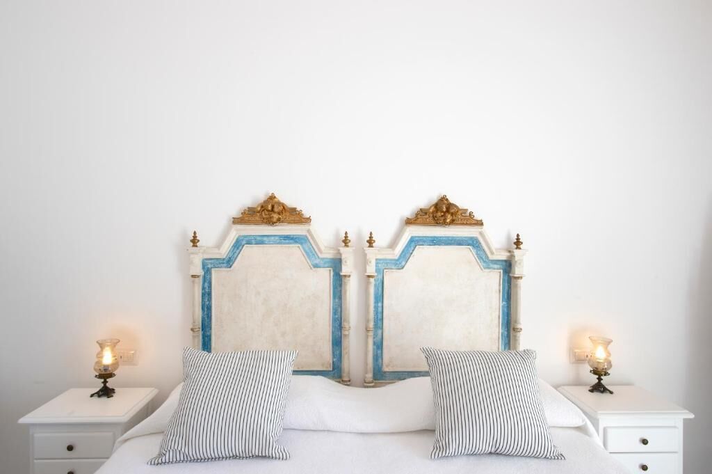 A double bed with a white and blue headboard, two bedside tables with lamps, and striped pillows.