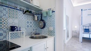 Une cuisine équipée d’un évier, d’une cuisinière et de casseroles suspendues. Elle comprend un plan de travail blanc et un crédence à motifs.