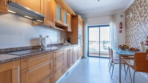 Een moderne keuken met houten kastjes, een granieten aanrechtblad en een eethoek met een tafel en stoelen.