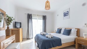 Een moderne slaapkamer met een bed, nachtkastjes, een televisie en een bureau.