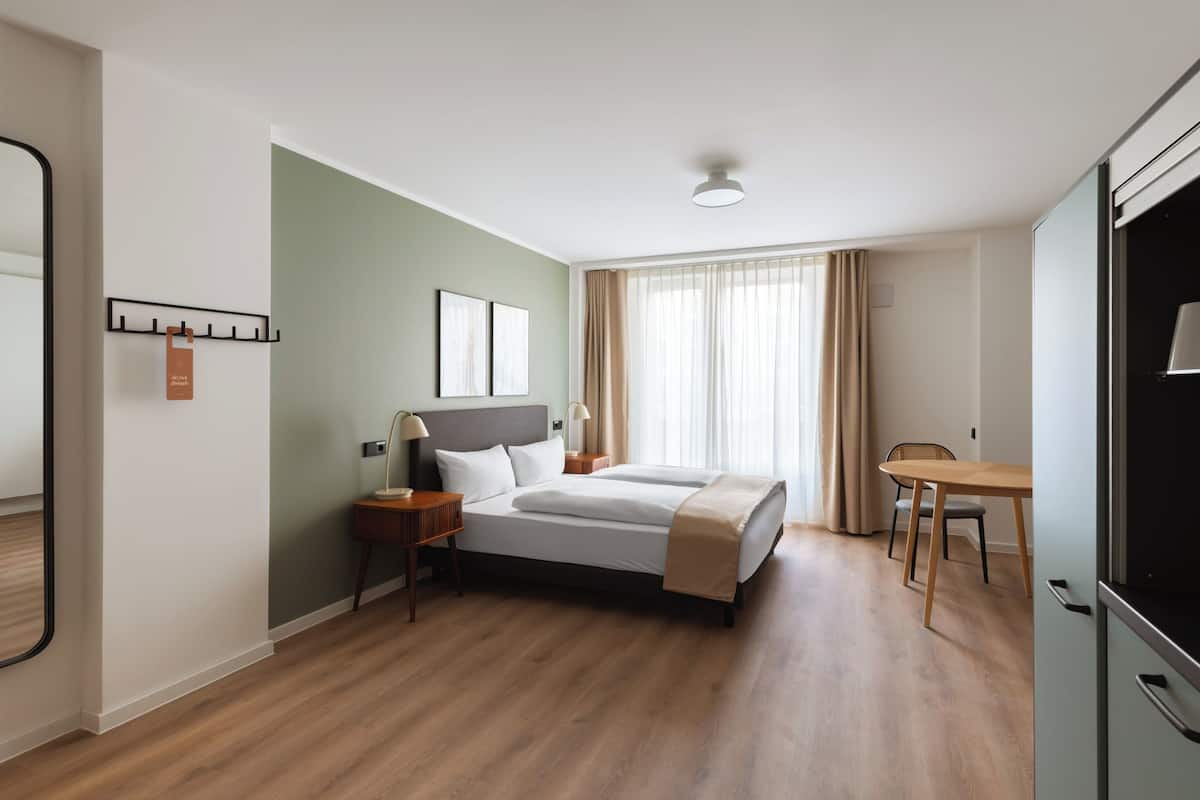 Habitació d'hotel amb un llit, taules de nit, escriptori i una cadira.