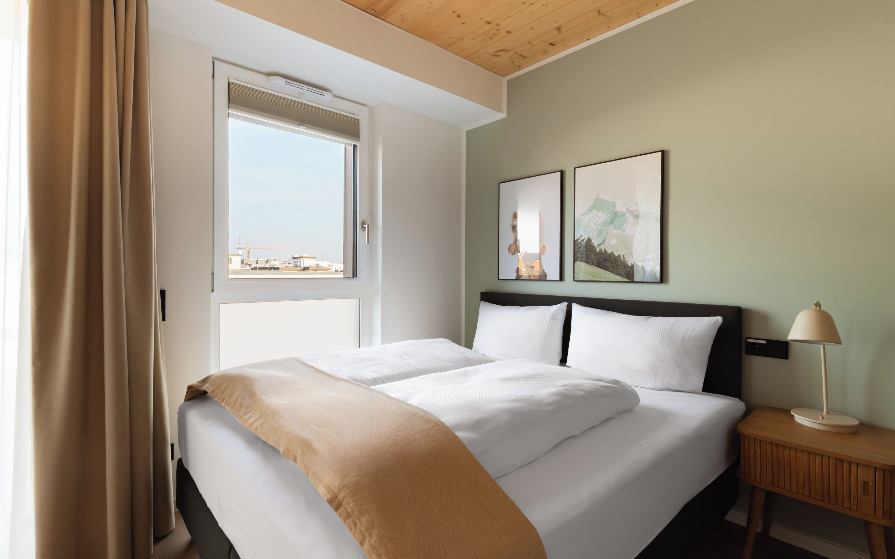 Ein Hotelzimmer mit einem Bett, einem Nachttisch, einer Lampe und zwei gerahmten Bildern an der Wand.