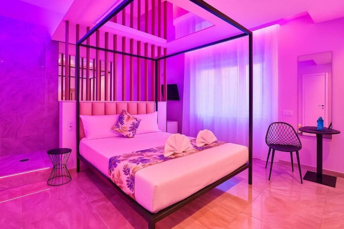 A modern bedroom with a four-poster bed, a small round table, and a chair.